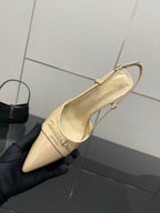 Beige point-toe slingback shoe held from side, showing logo on insole