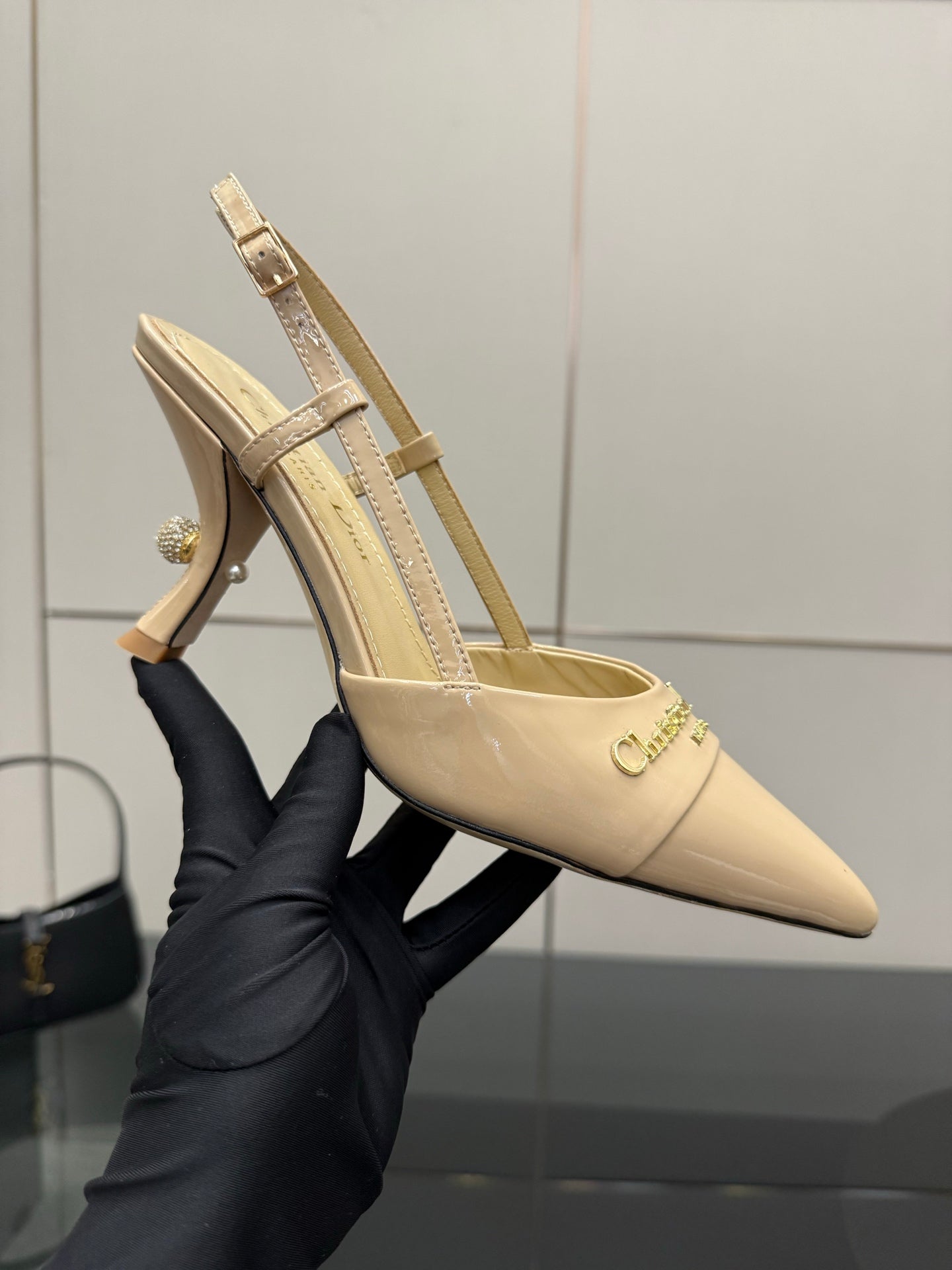 Beige patent point-toe slingback heel with ankle strap and gold-tone hardware