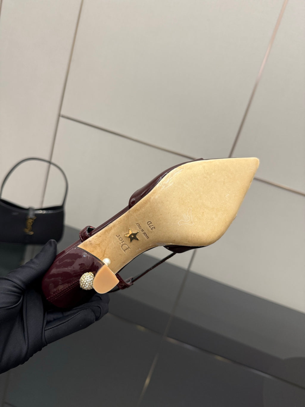 Dior ladies burgundy slingback heel held close, sole and heel tip visible.