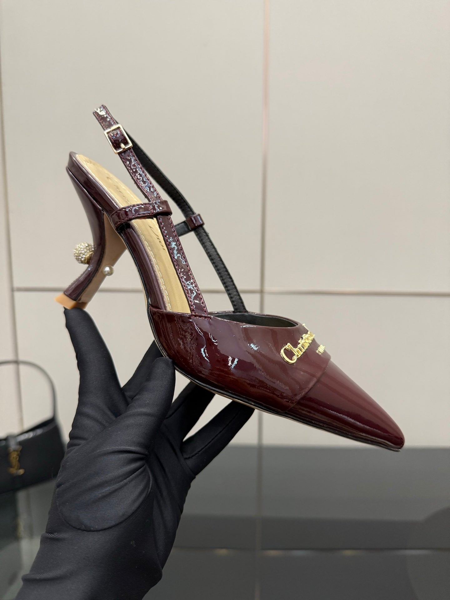 Dior ladies burgundy slingback heels held in hand, showing glossy toe.