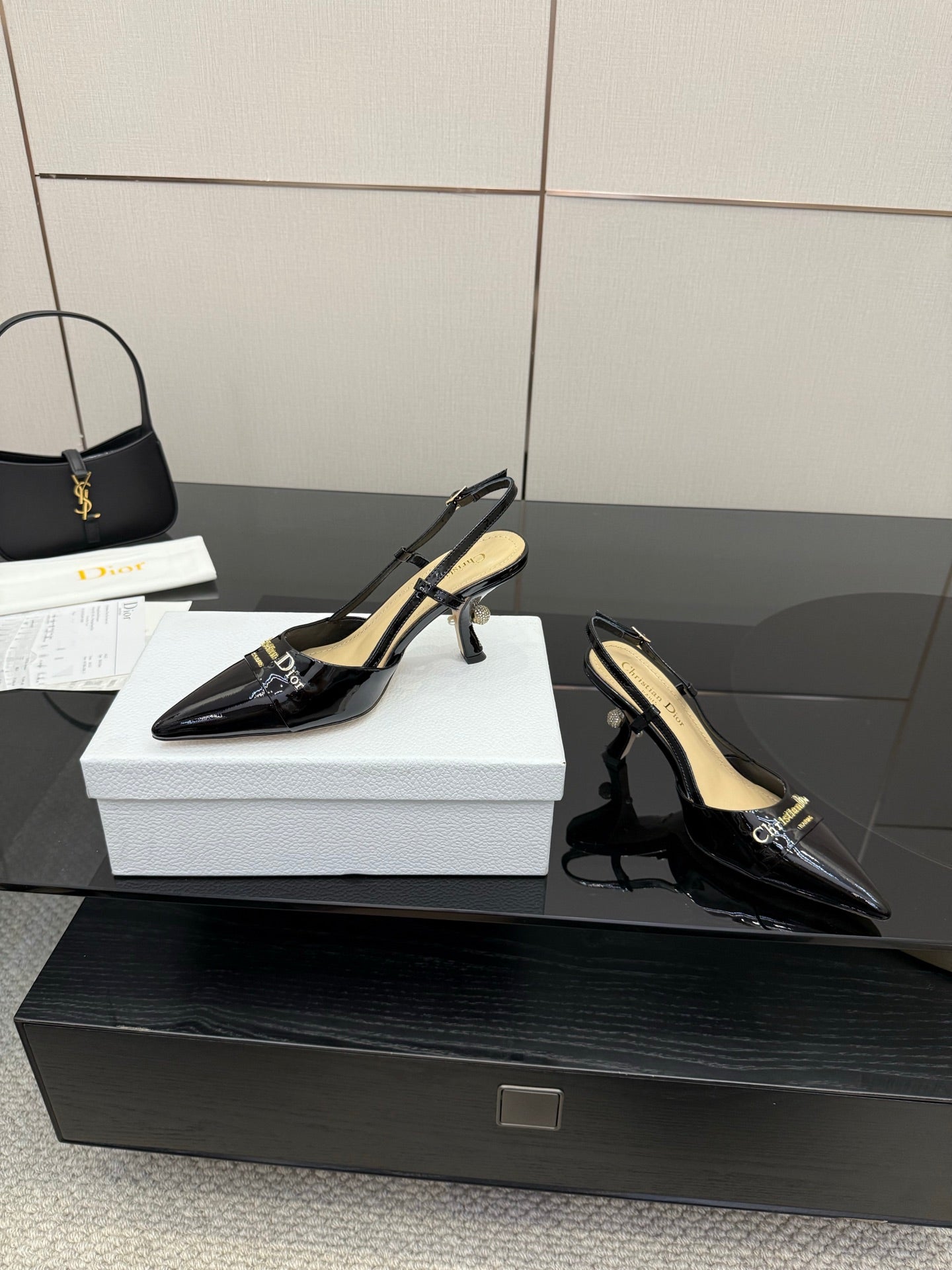 Black patent leather point-toe slingback heels with gold-tone detail, side view pair