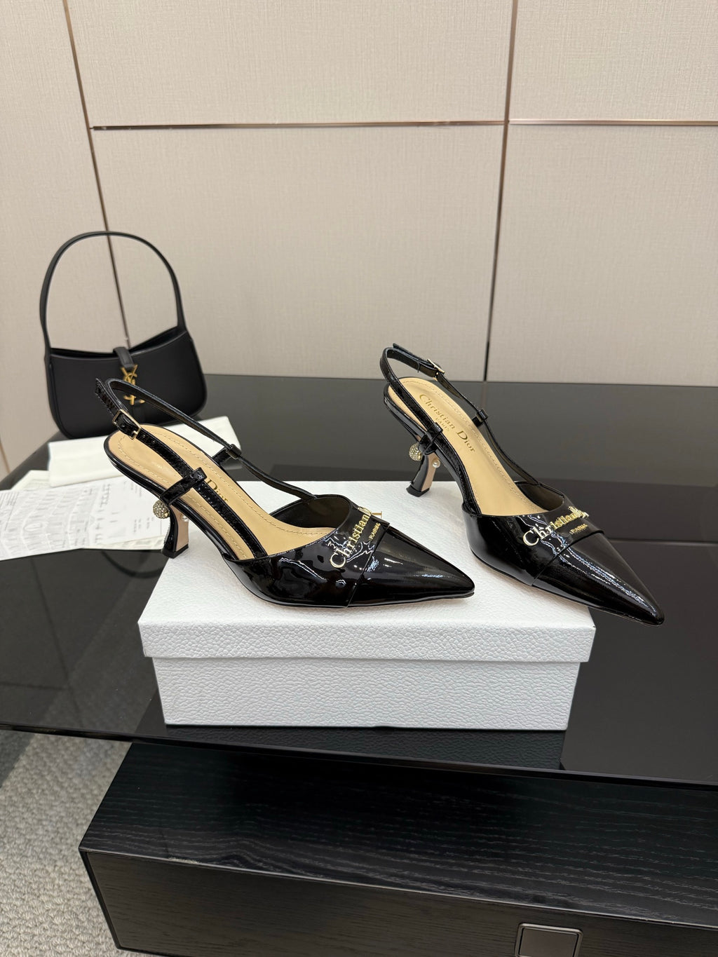 Black patent leather point-toe slingback heels with slim heel, pair on shoebox top
