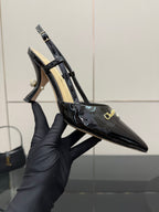 Black patent leather slingback heel shown in hand, pointed toe and ankle strap