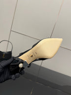 Black patent leather slingback heel underside in hand, cream insole with gold markings