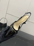 Black patent leather slingback heel in hand, interior lining and strap visible
