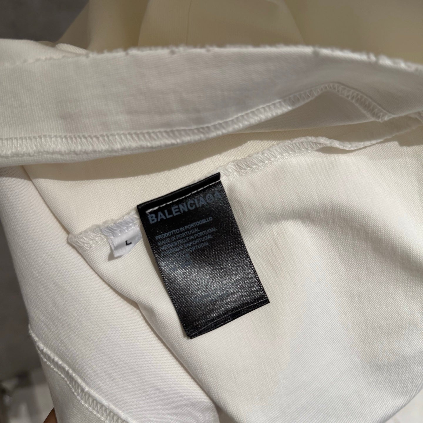 White T-shirt hem with stitched edge and BALENCIAGA care tag