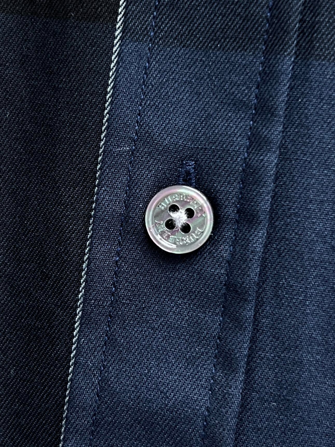 Close-up of button and placket on navy plaid long-sleeve shirt