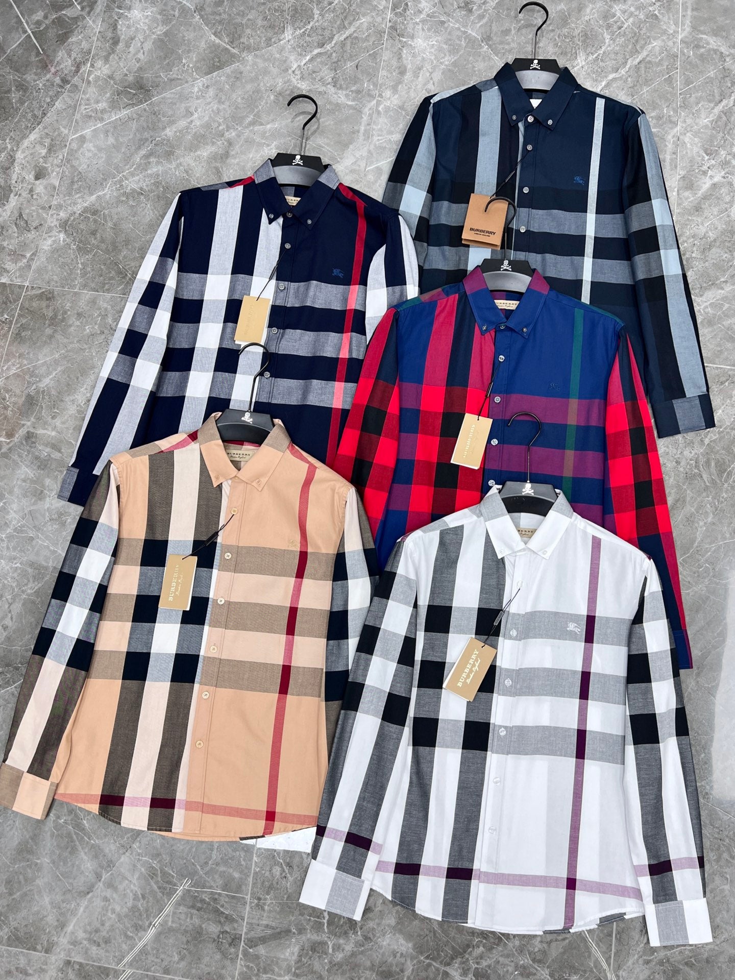 Plaid long-sleeve shirts on hangers in blue, red, navy, and beige check patterns