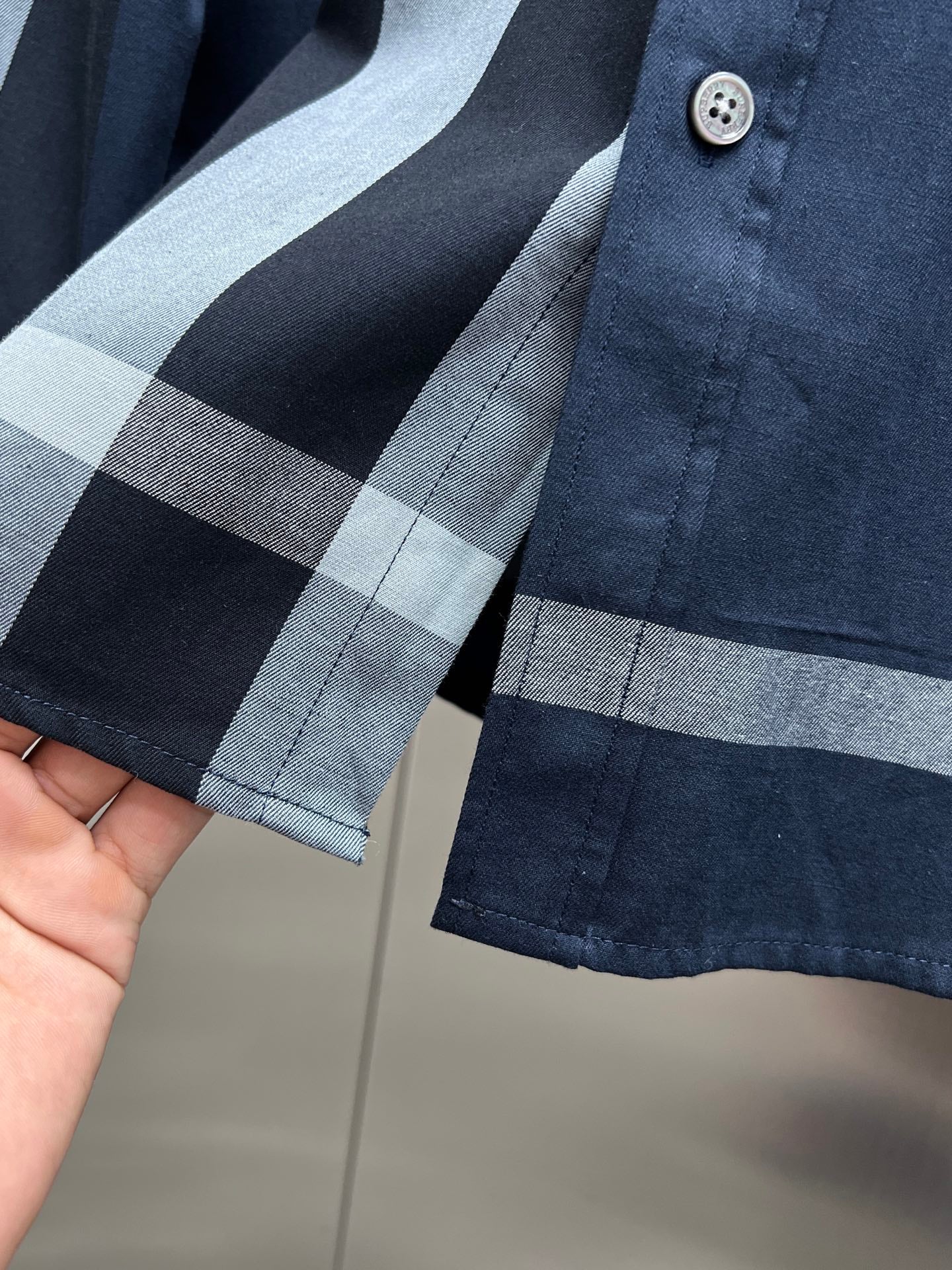 Navy long-sleeve shirt with light blue and gray plaid cuffs and buttoned placket