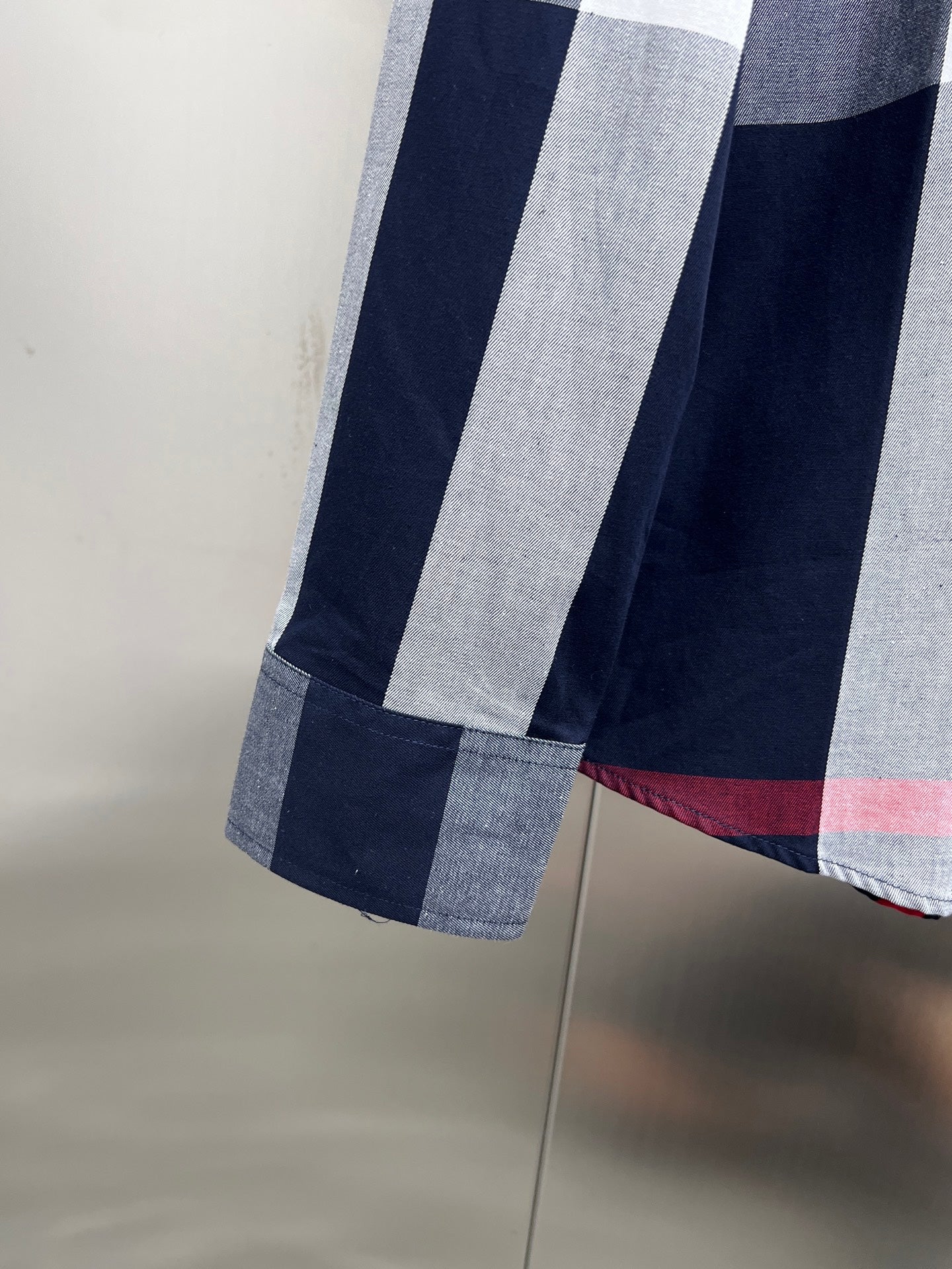 Long-sleeve plaid shirt hem and sleeve cuff, navy and white blocks with red line