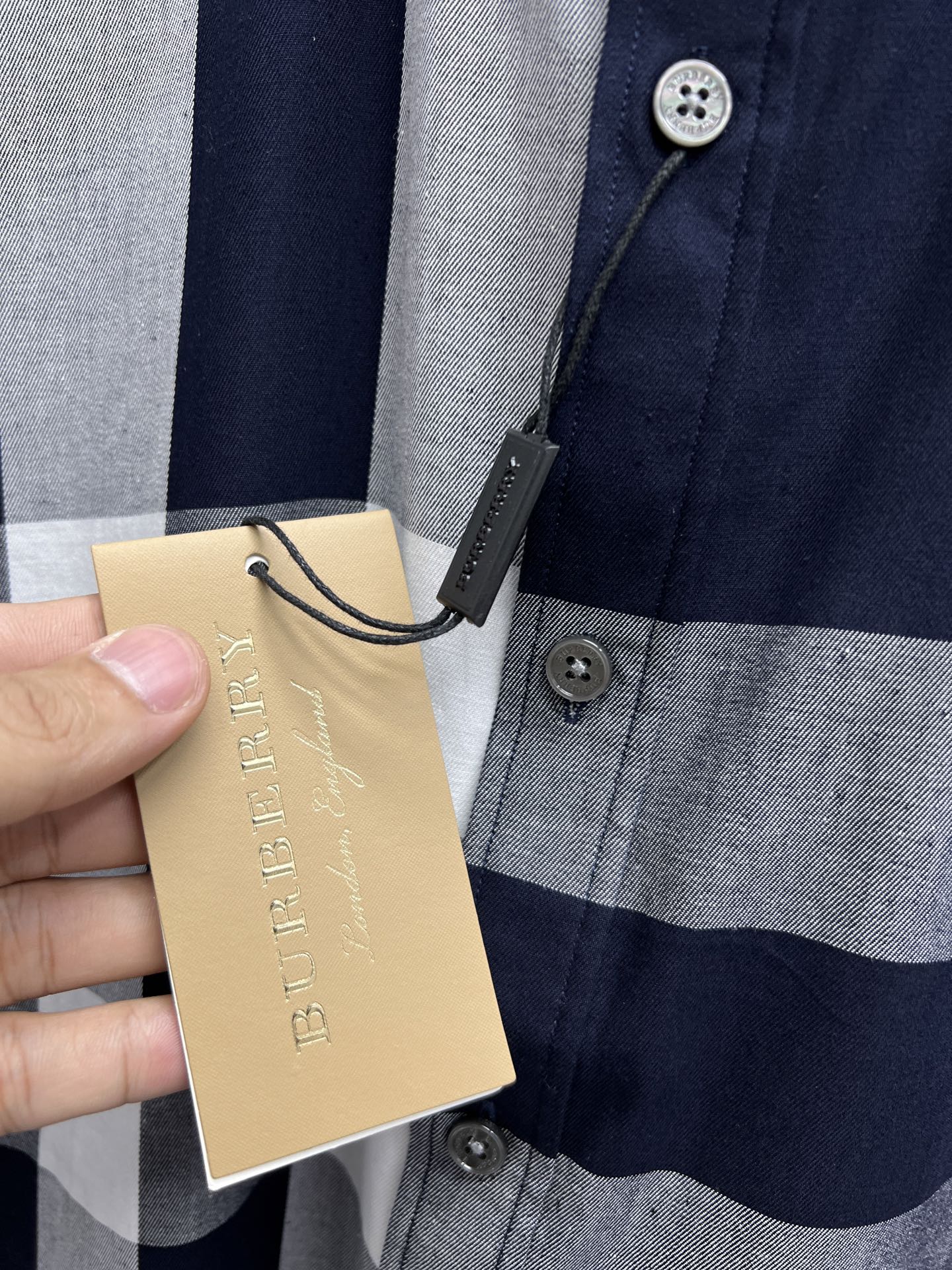 Long-sleeve plaid shirt front with buttons and hanging tan price tag
