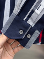 Long-sleeve check shirt cuff with button placket, navy and gray stripes with red accent