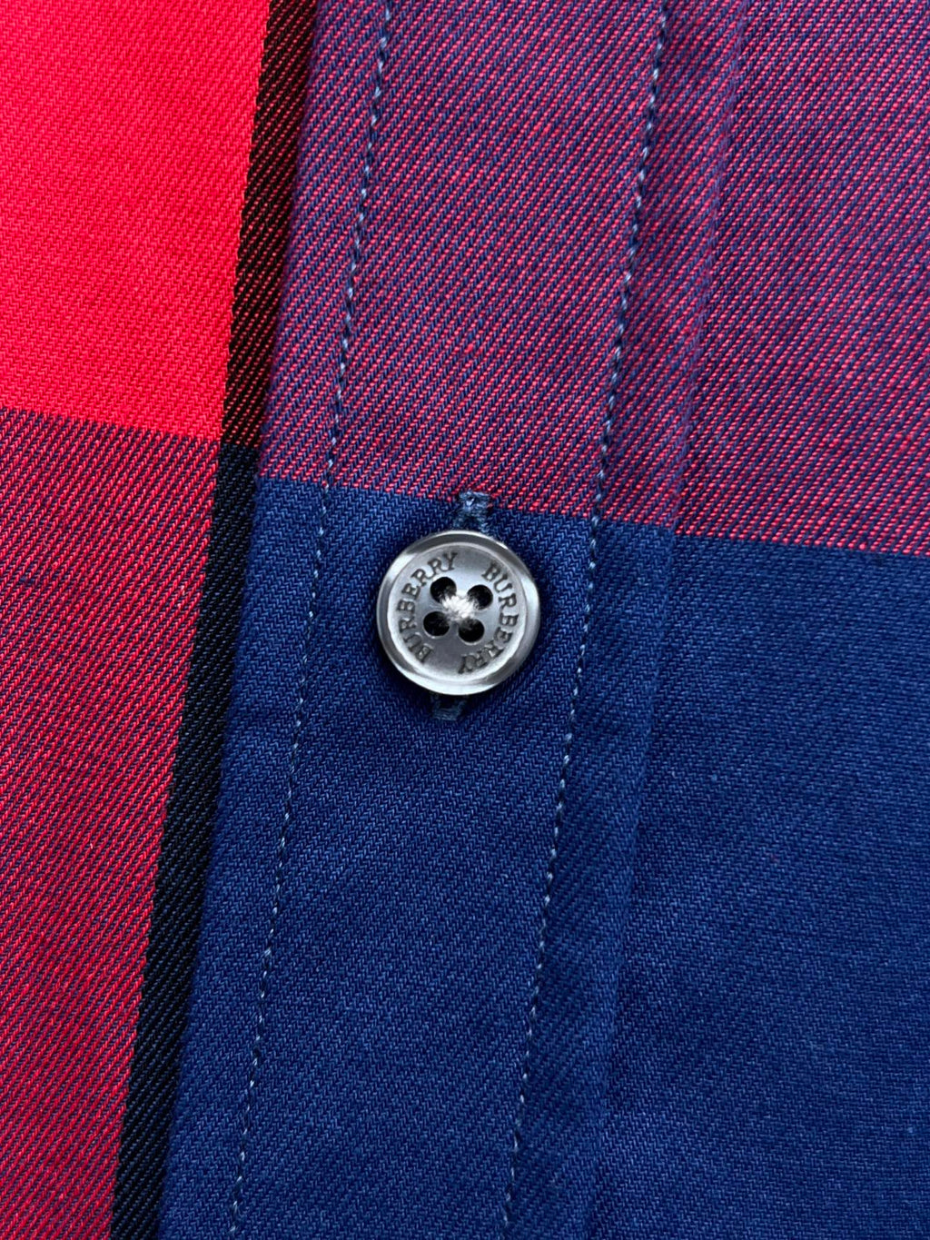 Button detail on plaid long-sleeve shirt in blue, red, and purple check panels