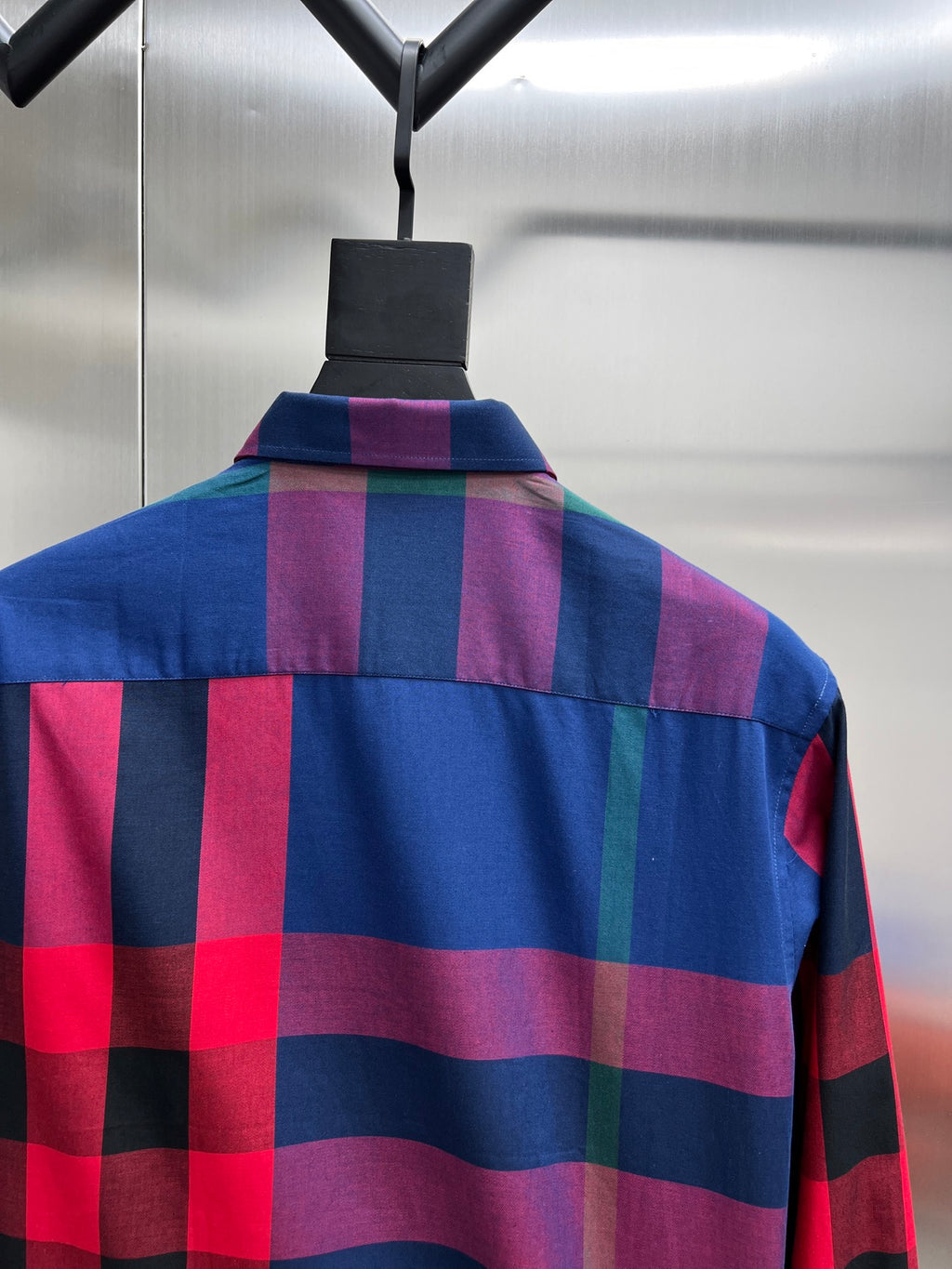 Blue and magenta checkered long-sleeve shirt on a hanger, back view