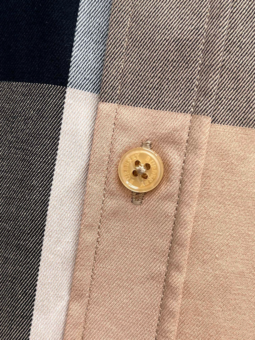 Burberry plaid shirt close-up of gold button on beige placket