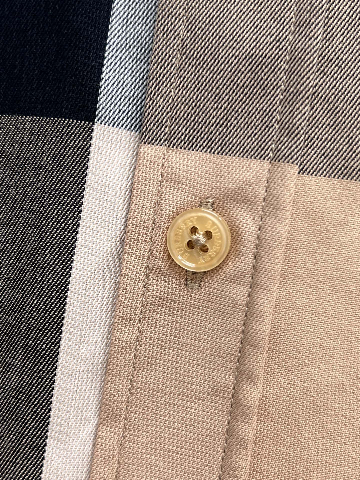 Burberry plaid shirt close-up of gold button on beige placket