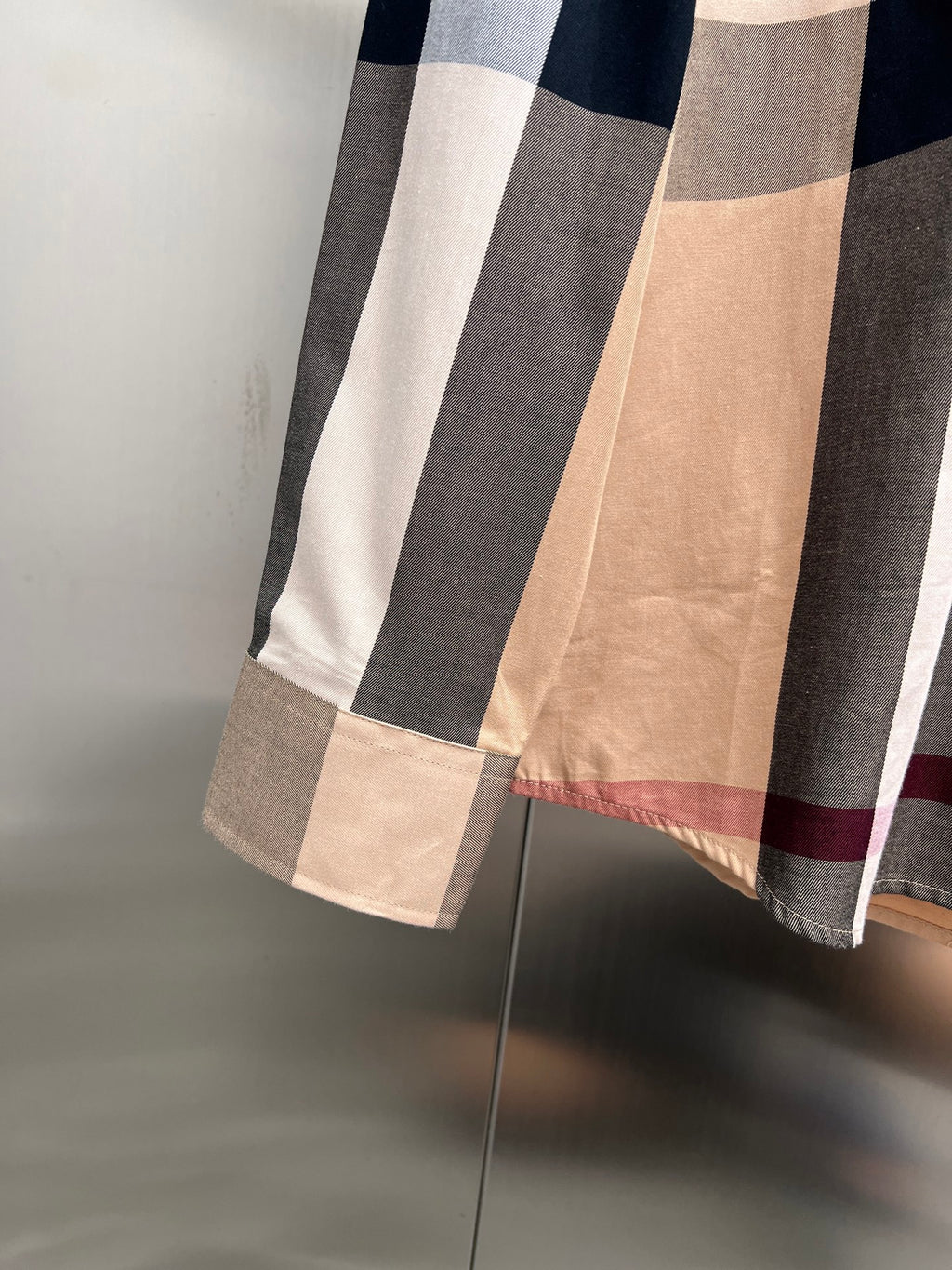 Burberry plaid button-up shirt hem detail in beige with navy, white, and red stripes