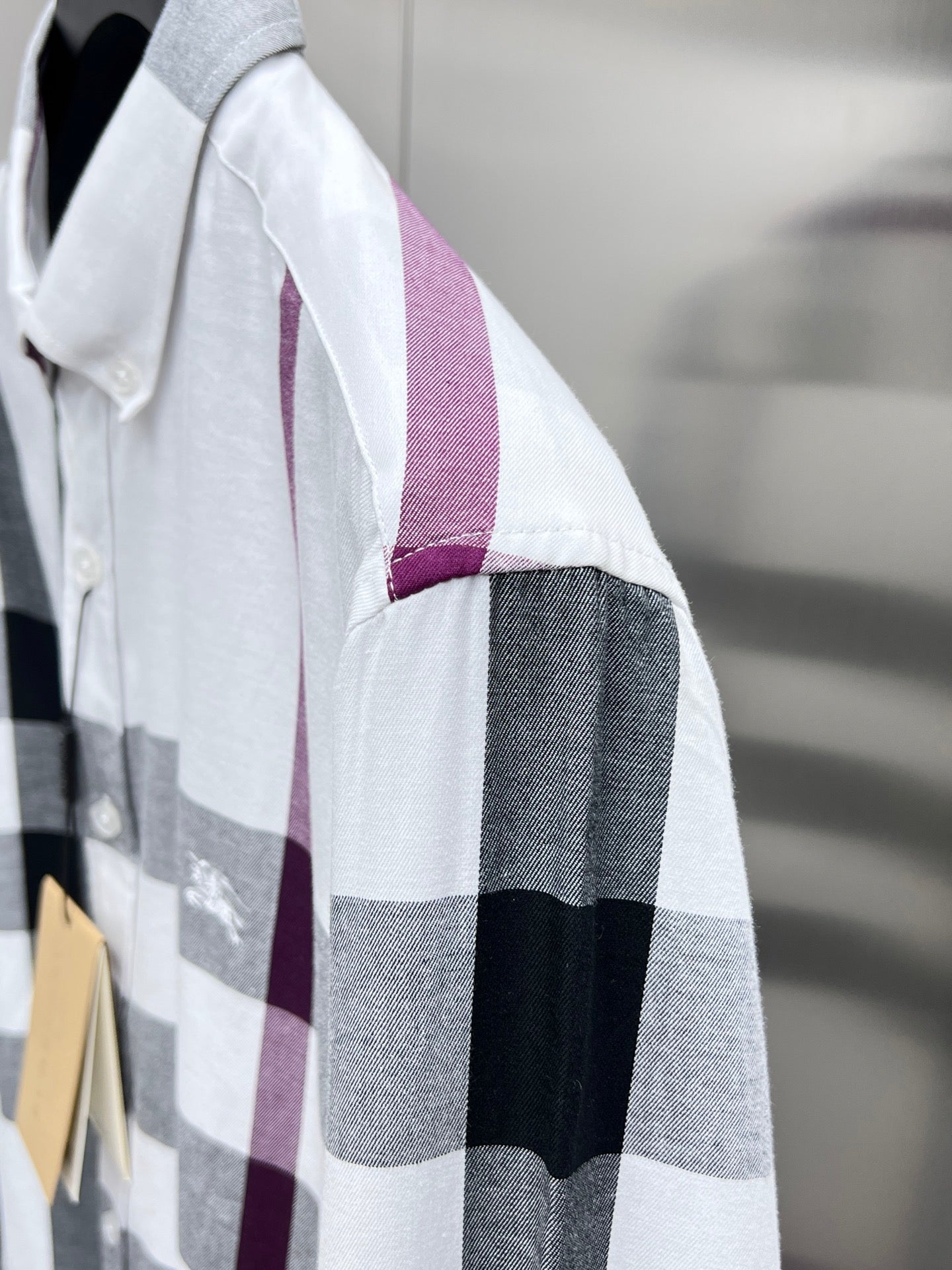 Long-sleeve button-up shirt sleeve in white, gray, and maroon plaid.