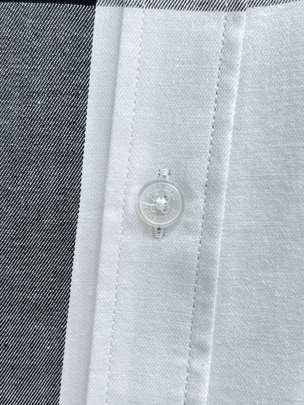 Button and placket detail on white plaid shirt.