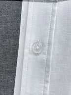 Button and placket detail on white plaid shirt.