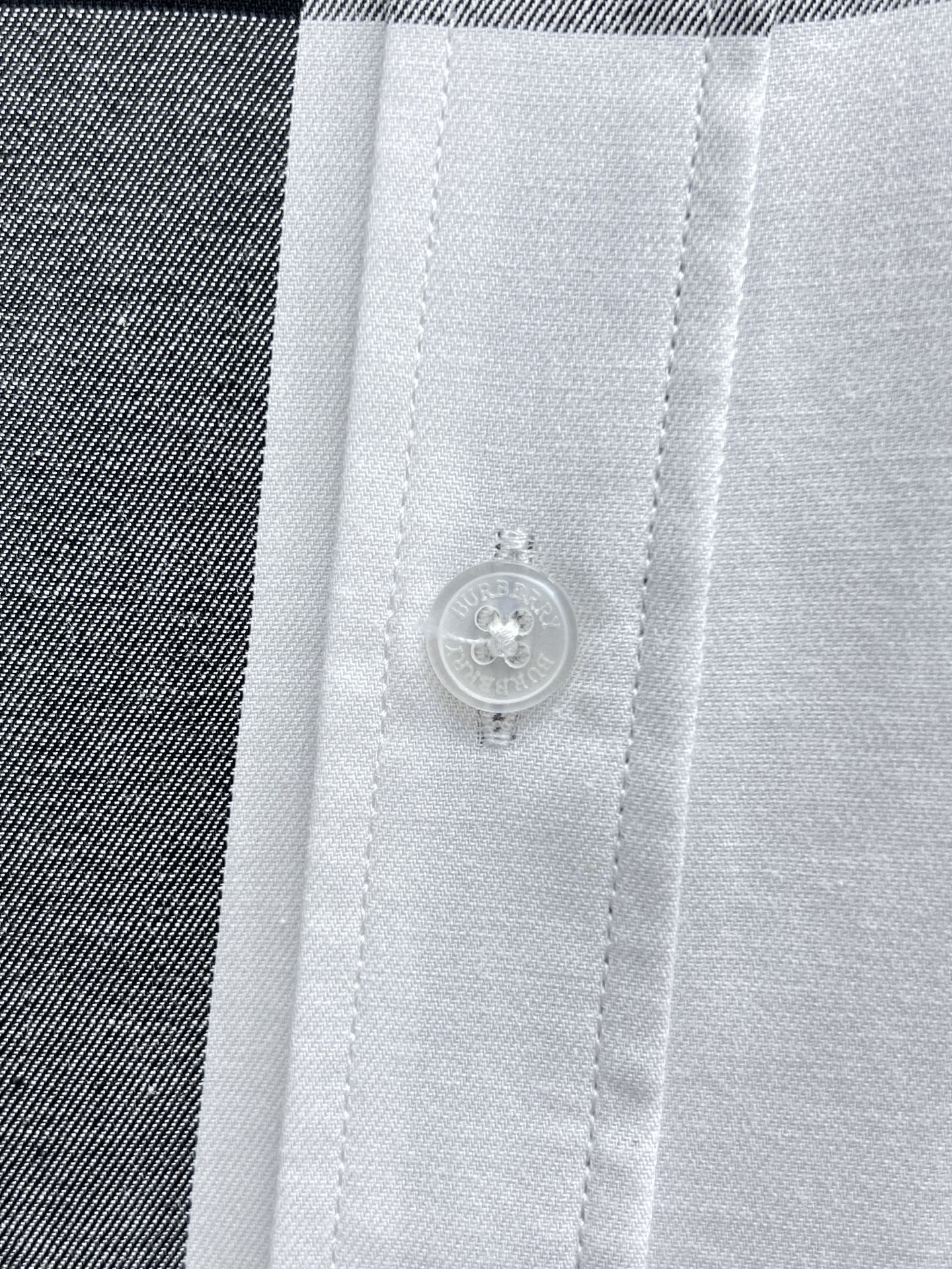 Button and placket detail on white plaid shirt.