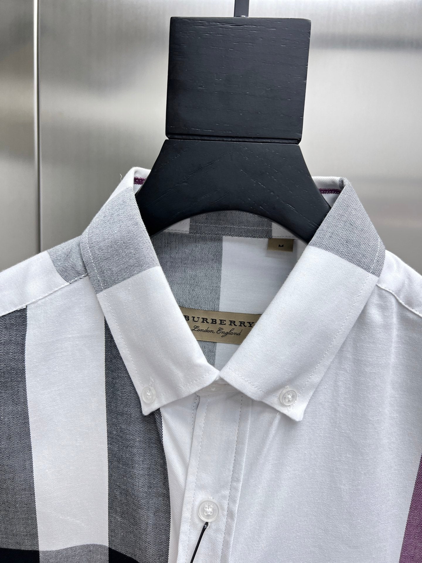 Burberry button-up shirt collar in white, black, and light gray plaid.