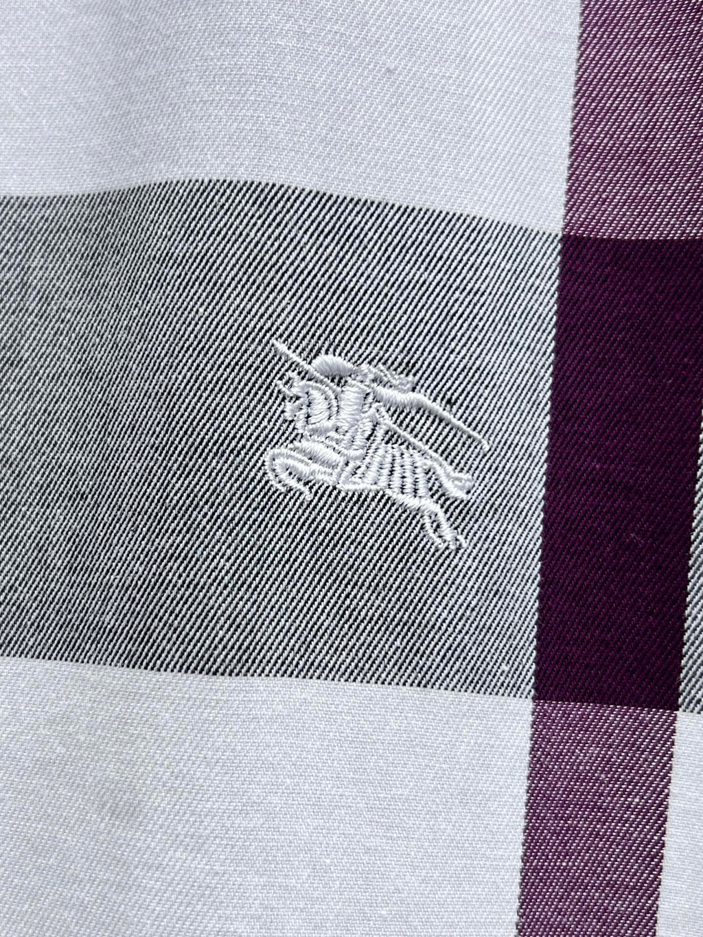 Embroidered horse logo on plaid fabric, gray and maroon stripe.