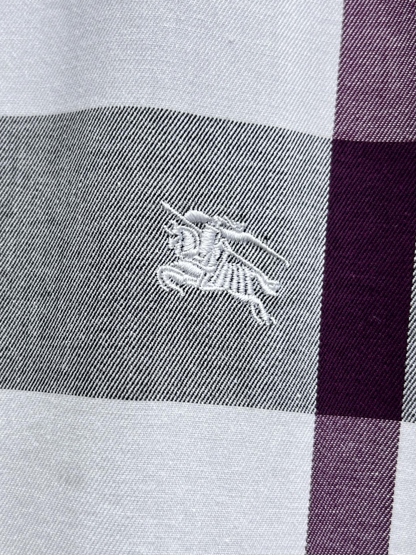 Embroidered horse logo on plaid fabric, gray and maroon stripe.