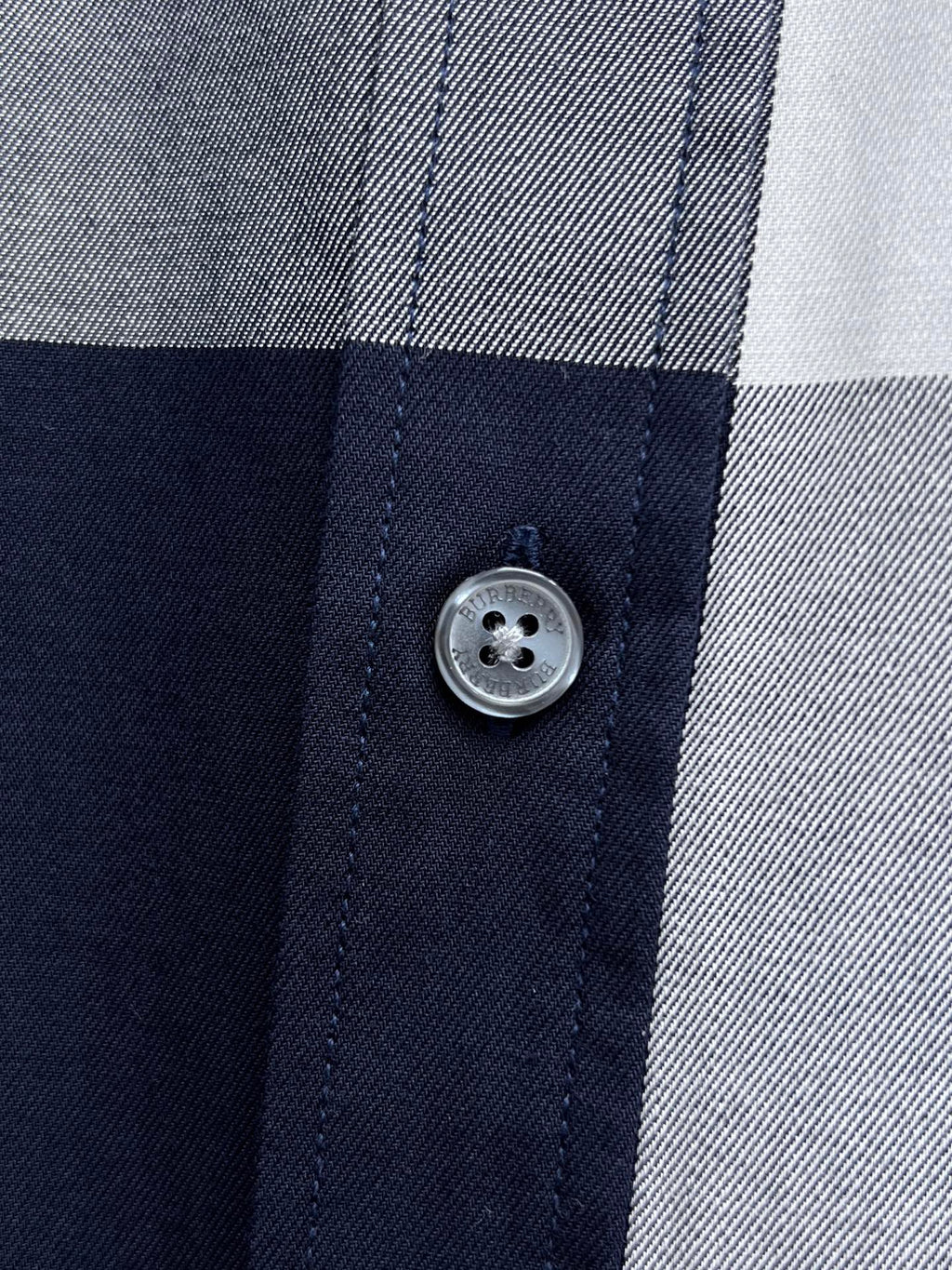 Close-up of button placket on navy-and-white plaid button-up shirt