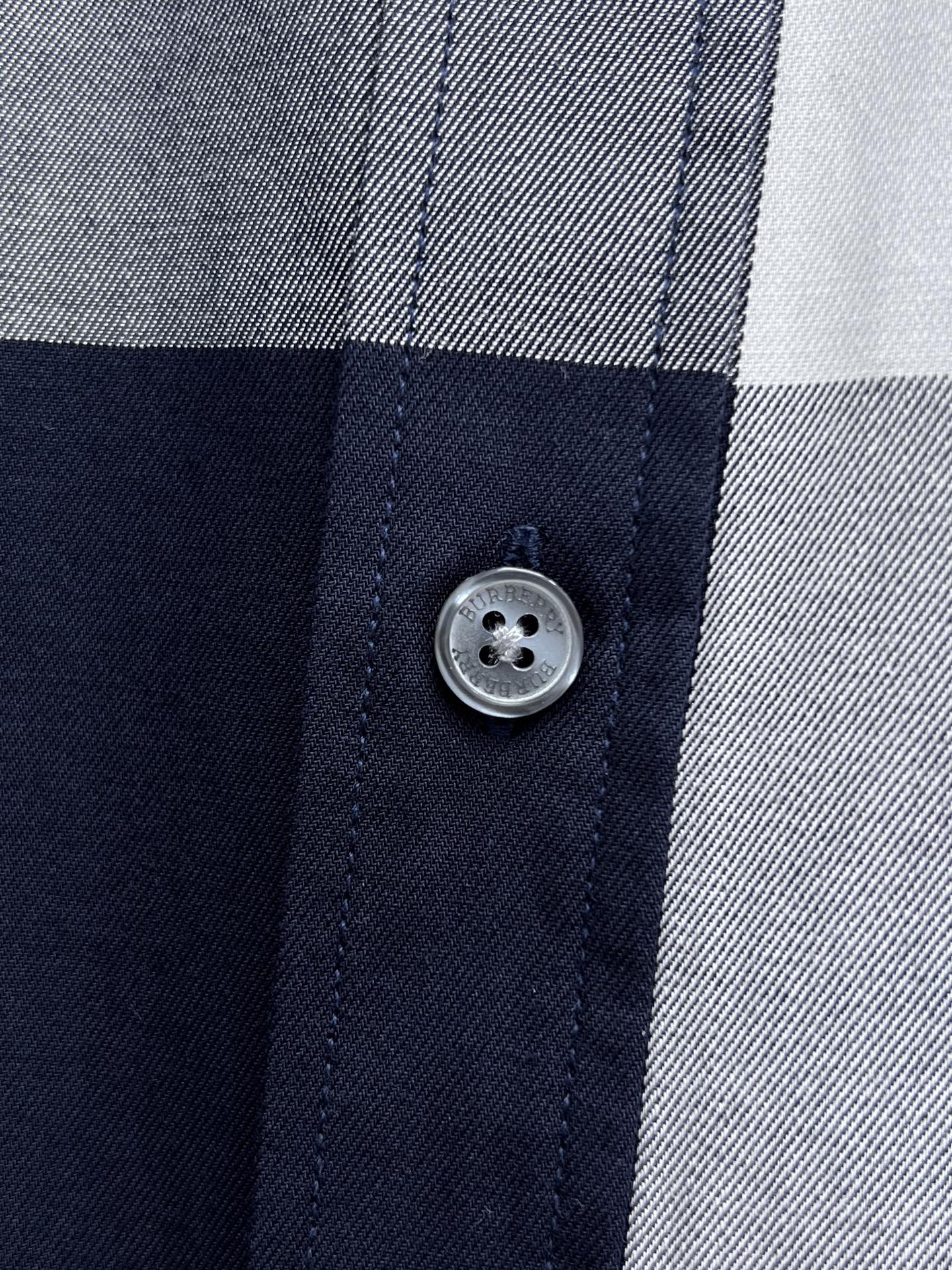 Close-up of button placket on navy-and-white plaid button-up shirt