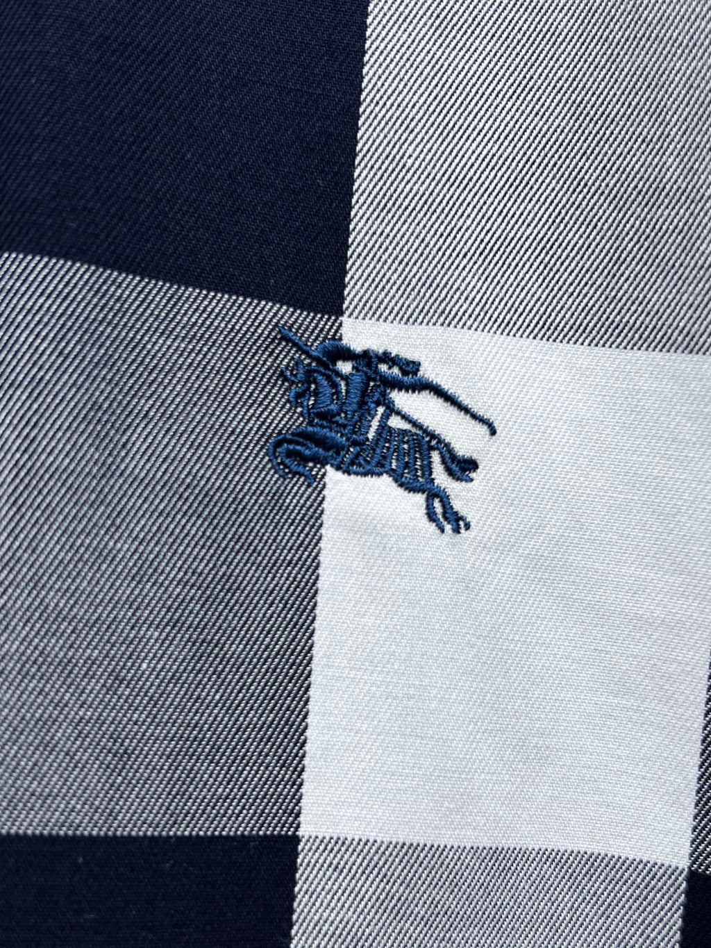 Embroidered horse logo on navy-and-white plaid fabric