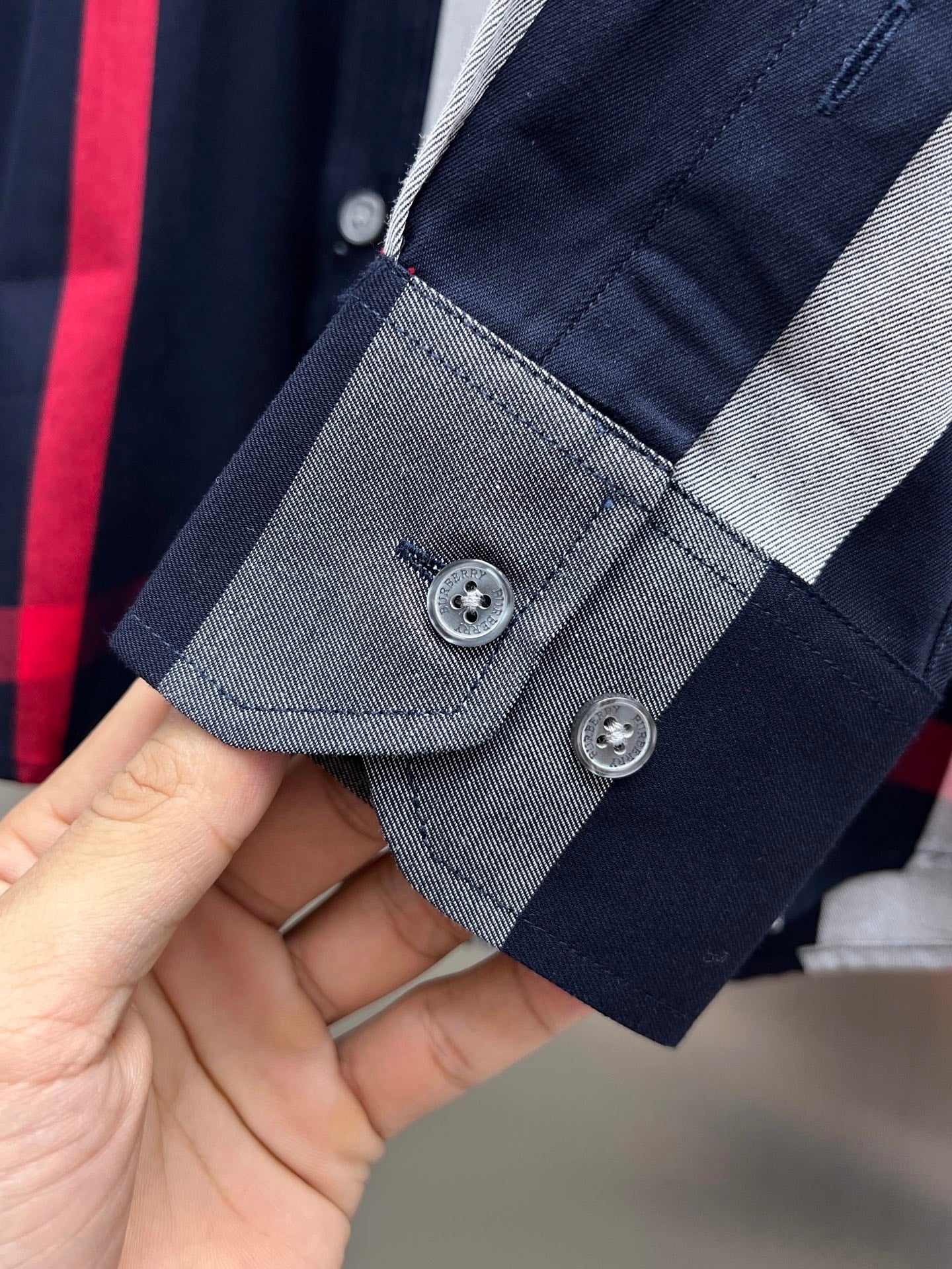 Plaid shirt cuff and button placket, navy with gray and red accents