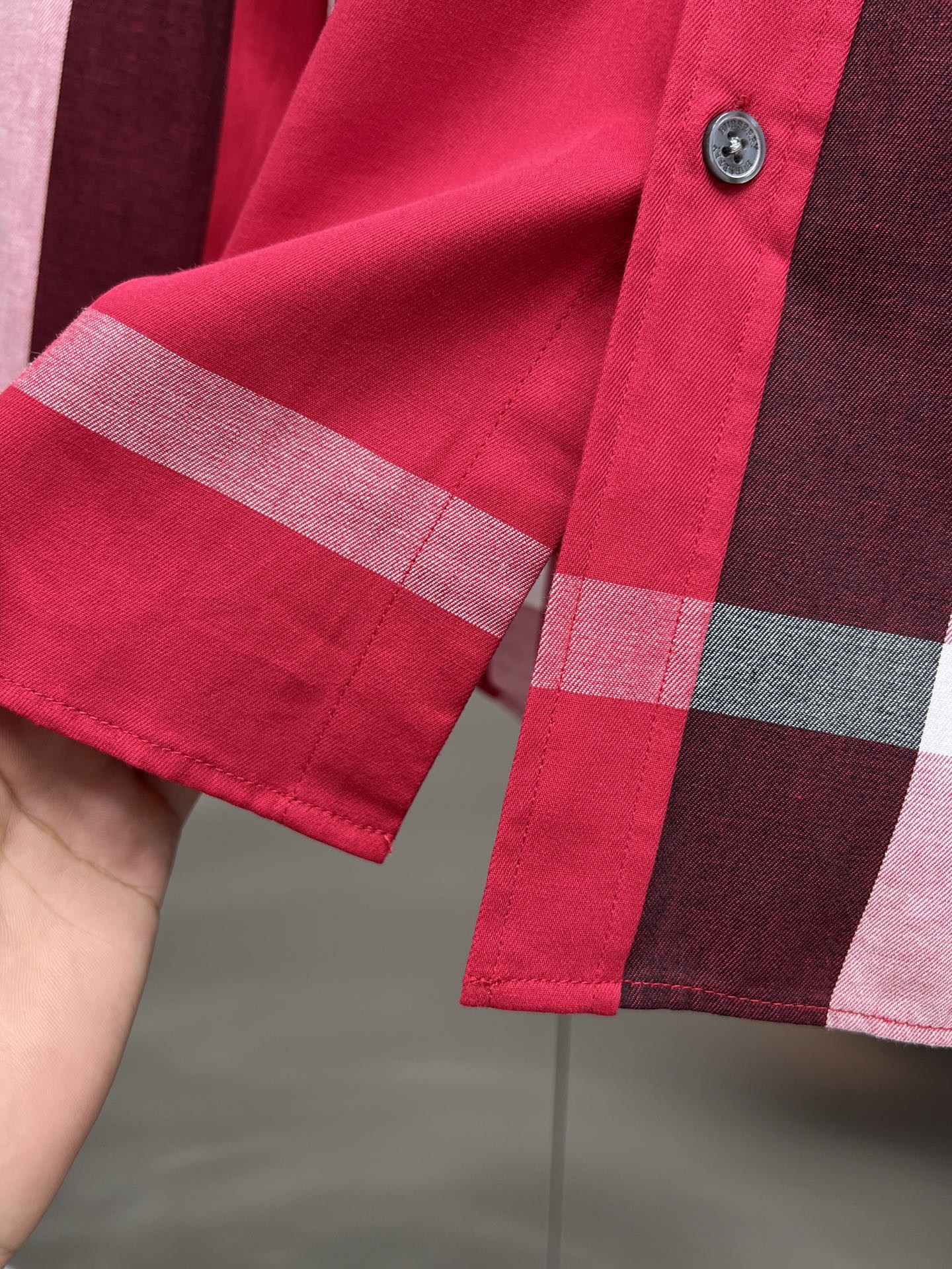 Long-sleeve shirt cuff with red plaid pattern and button detail