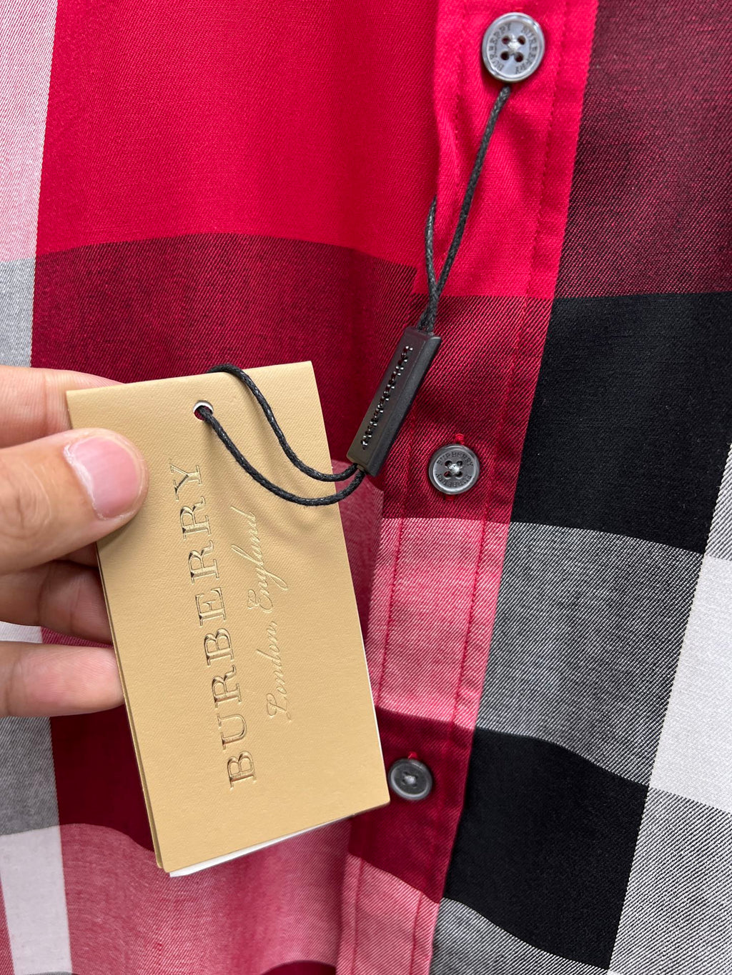 Burberry plaid shirt button placket detail with hanging price tag
