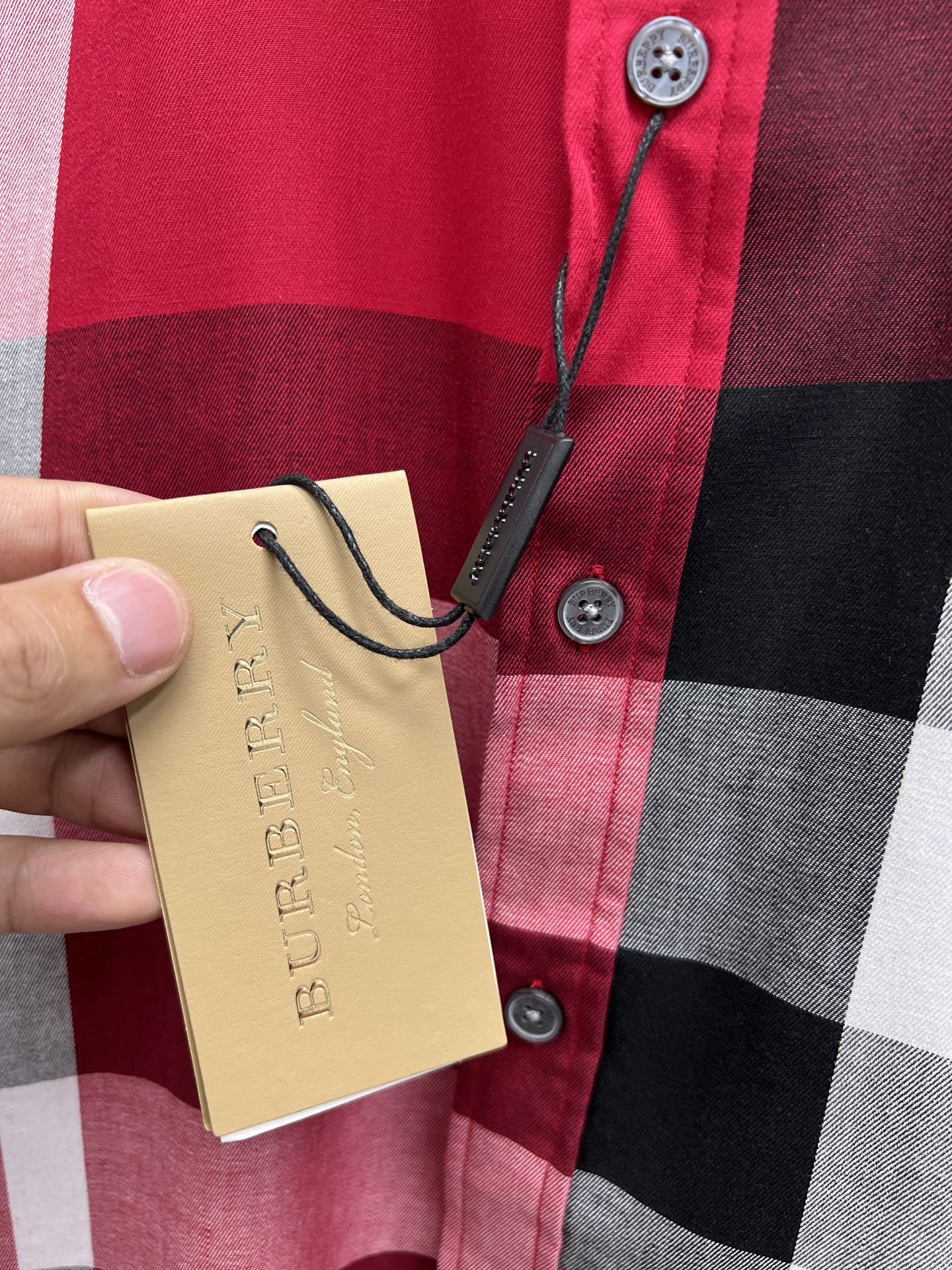 Burberry plaid shirt button placket detail with hanging price tag