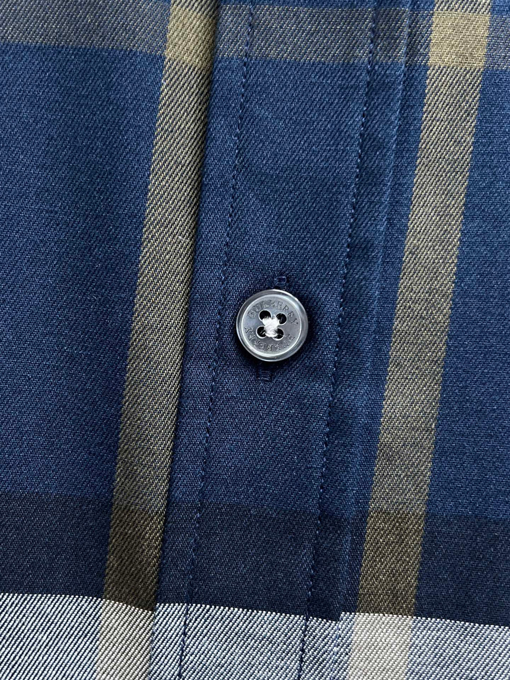 Close-up of Burberry check shirt with round button on blue plaid panel