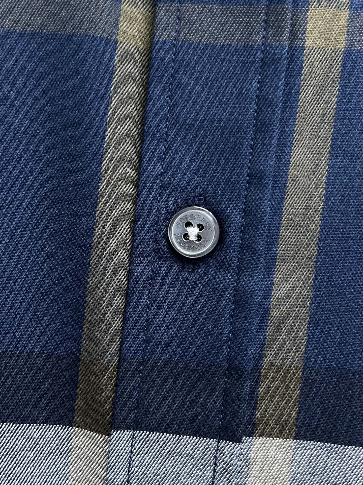 Close-up of Burberry check shirt with round button on blue plaid panel