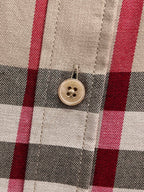 Close-up of button on beige plaid shirt placket, black white and red checks