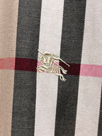 Embroidered logo detail on plaid shirt fabric, beige with black white and red