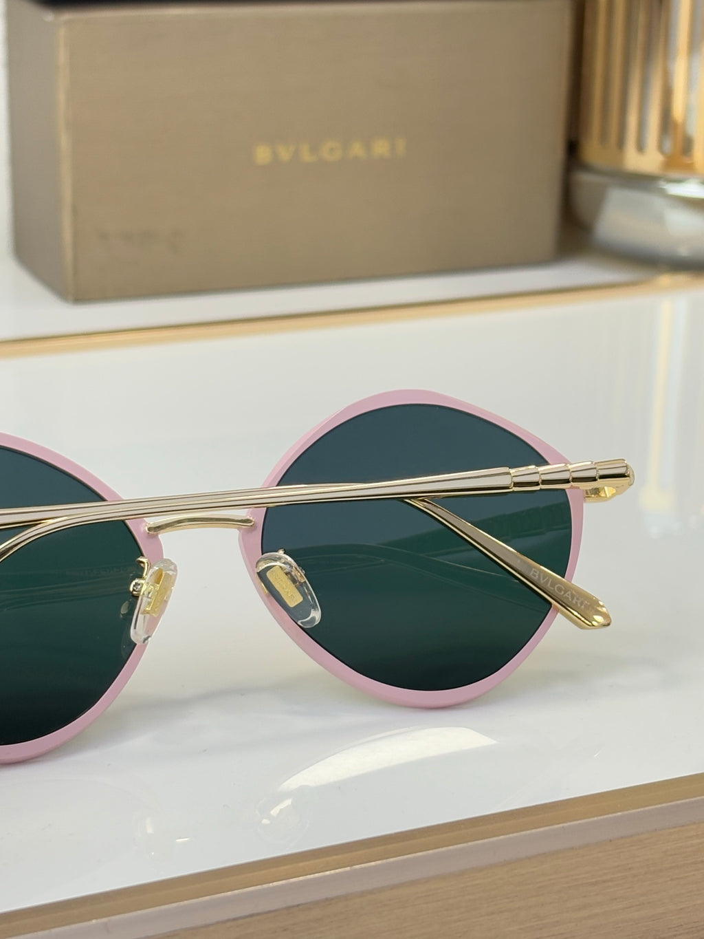 Round pink-trim eyeglasses with teal lenses and gold-tone metal arms