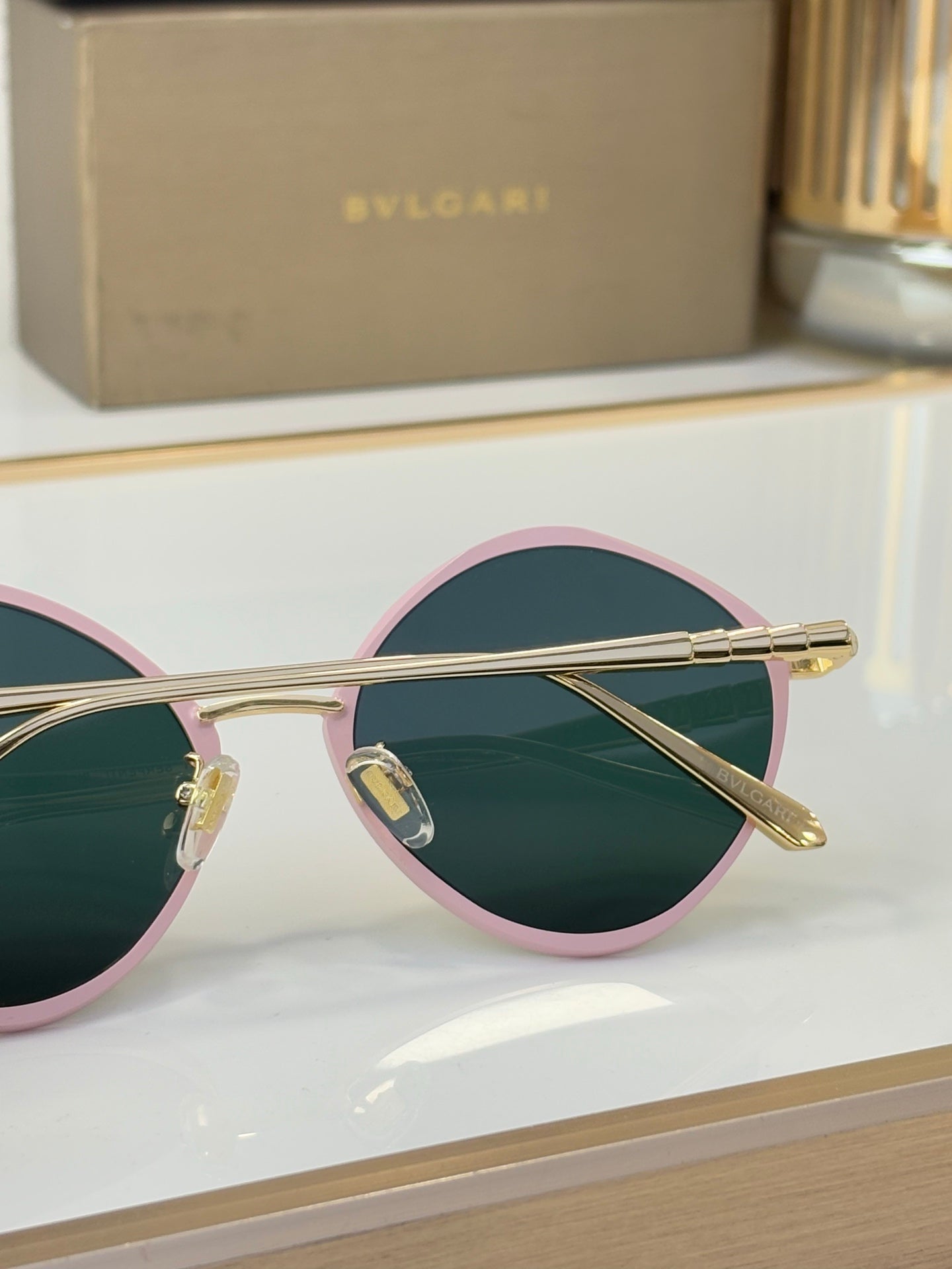 Round pink-trim eyeglasses with teal lenses and gold-tone metal arms