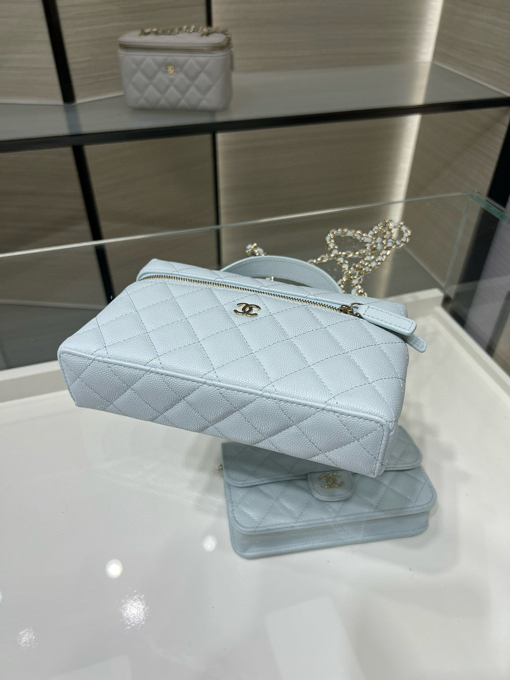 Light blue quilted handbag with gold zipper and chain strap across the front