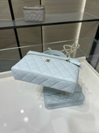 Light blue quilted handbag with gold zipper and chain strap across the front