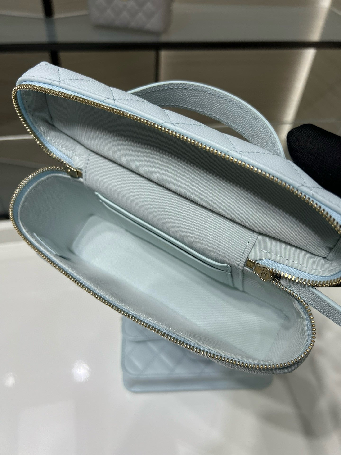 Light blue quilted handbag interior view with gold zipper trim and handle