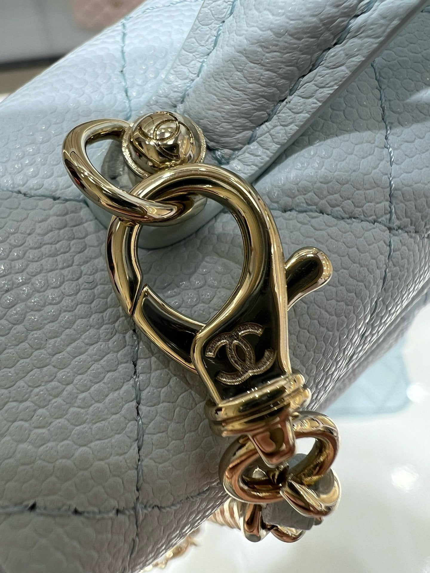 Light blue quilted handbag with gold chain clasp hardware and D-ring