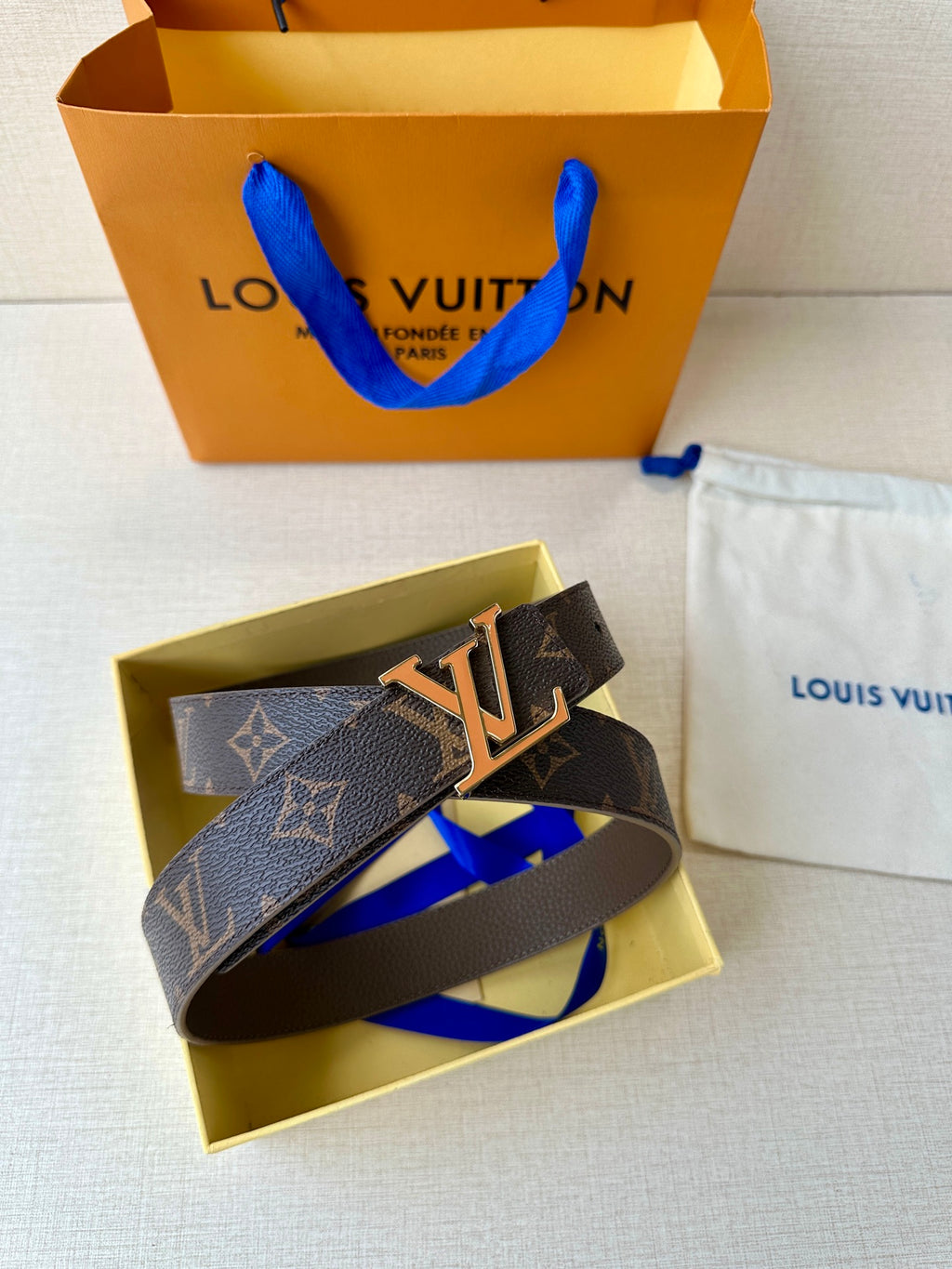 Monogram leather belt with gold-tone LV buckle, dark brown, looped.
