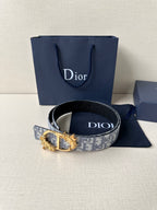 Blue-gray logo jacquard belt with ornate gold buckle and dark leather strap