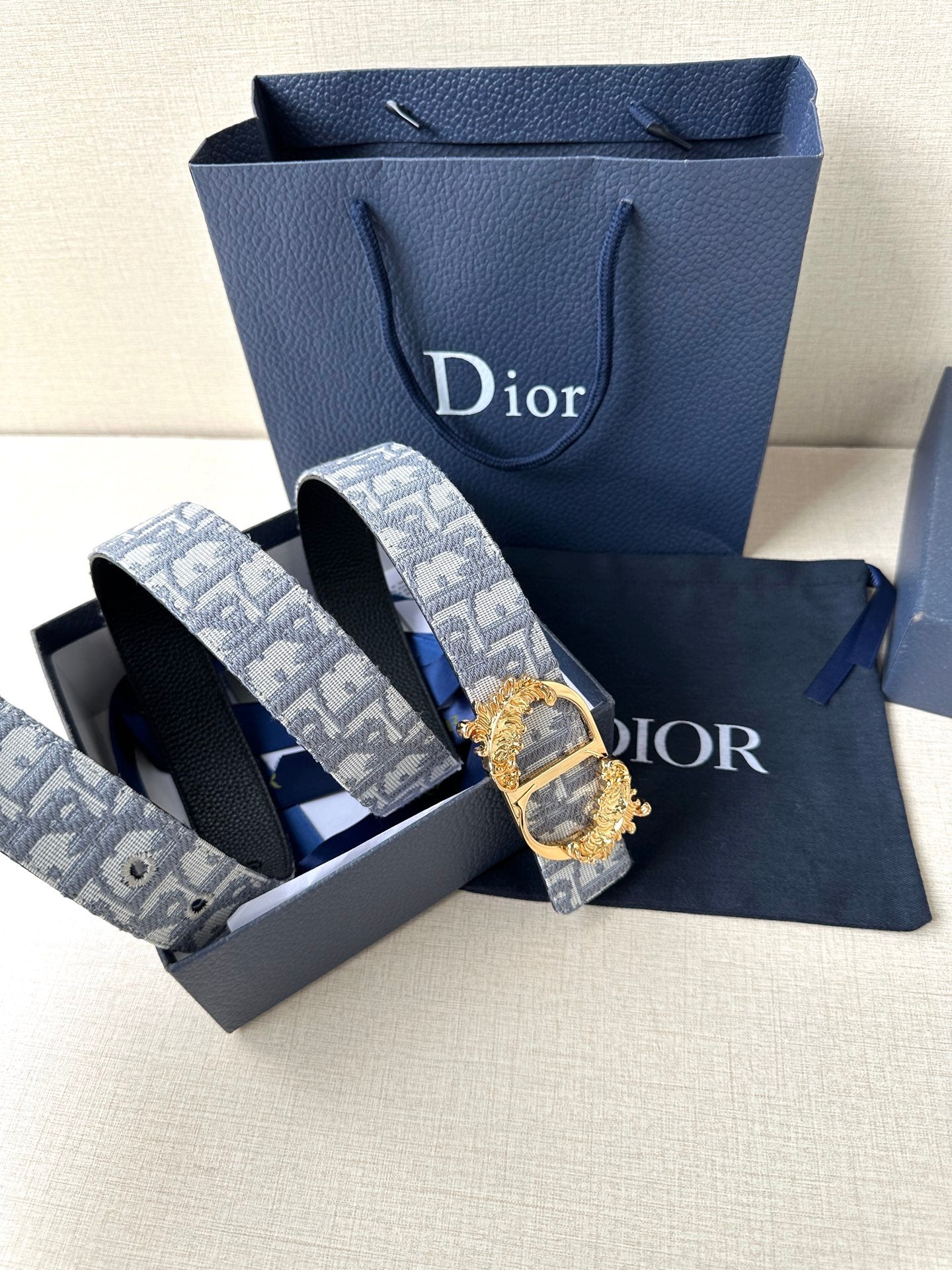 Logo jacquard belt with gold buckle alongside dark leather belt strap