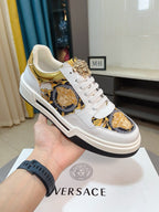 White lace-up sneakers with gold medallion print and textured gold collar accents.