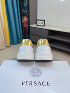 Back view of white sneakers with gold metallic heel caps and white rubber sole.